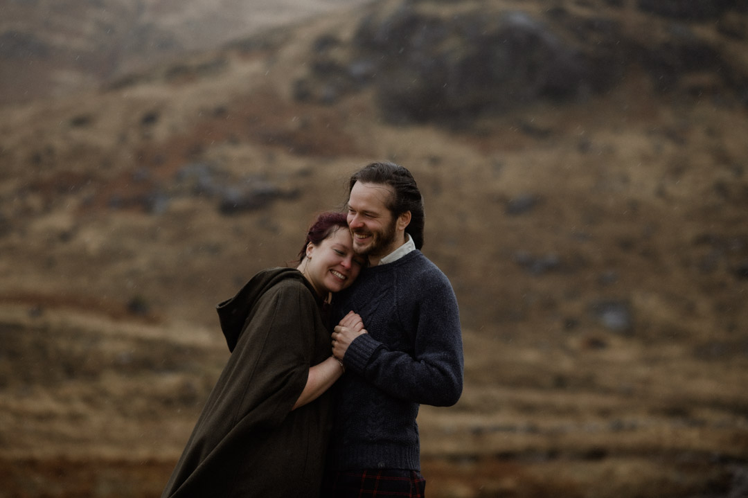 Wet elopement couple cuddling on Isle of Mull in the hills