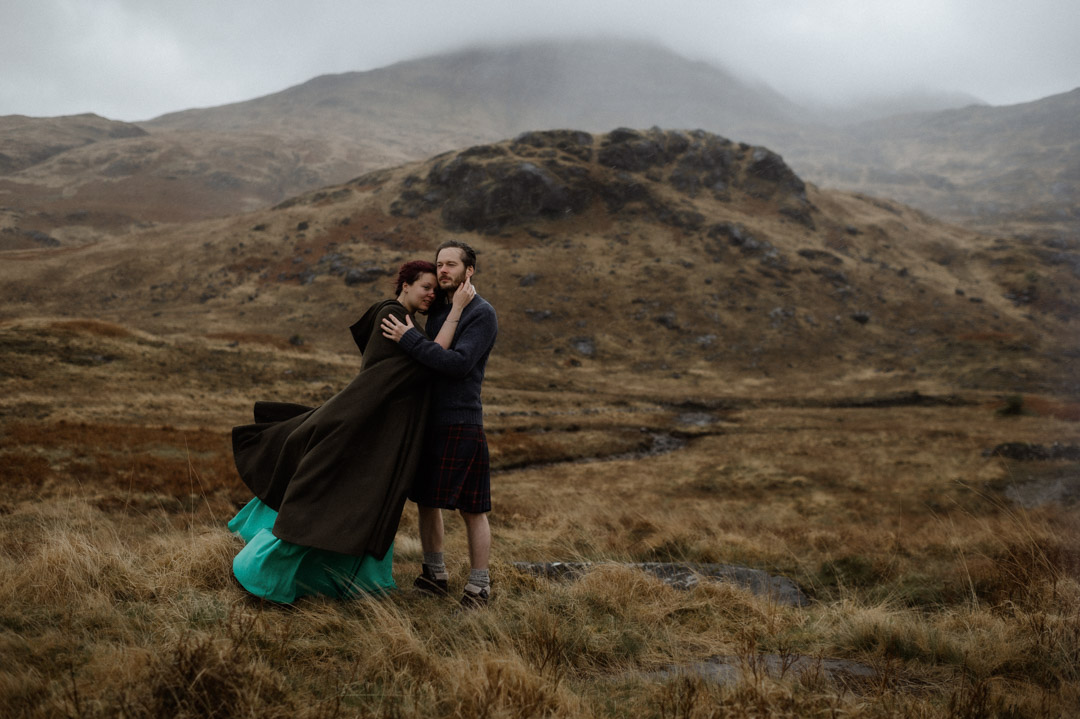 Wet elopement couple cuddling on Isle of Mull in the hills