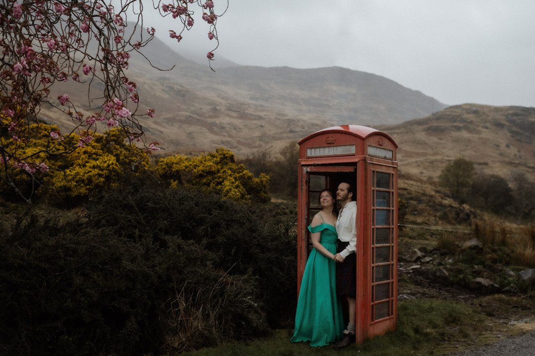 Wet elopement couple on Isle of Mull hiding in the telephone box for shelter