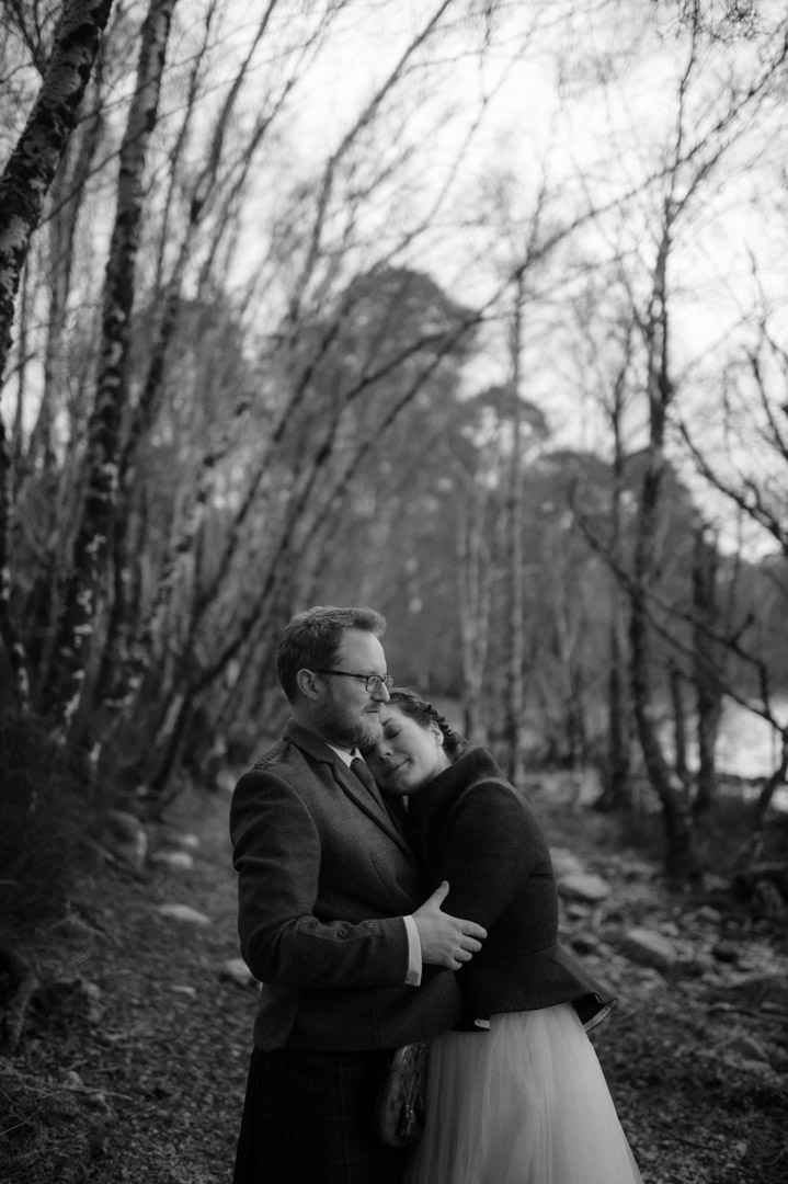 Outlander elopement couple by trees and loch in Scottish Highlands