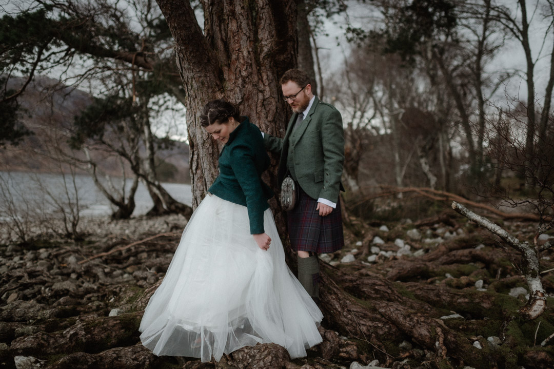 Outlander elopement couple by trees and loch in Scottish Highlands