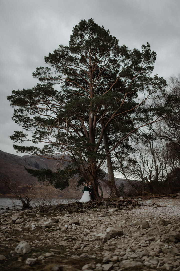 Outlander elopement couple by trees and loch in Scottish Highlands
