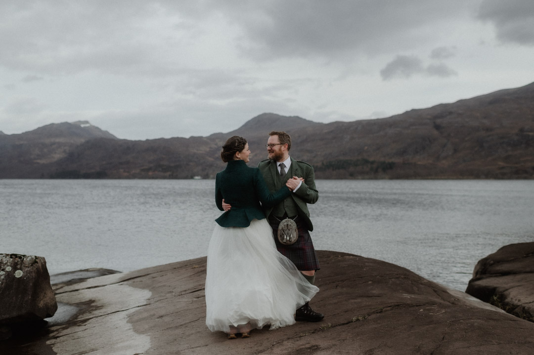 Winter elopement couple dancing by loch in Scottish Highlands