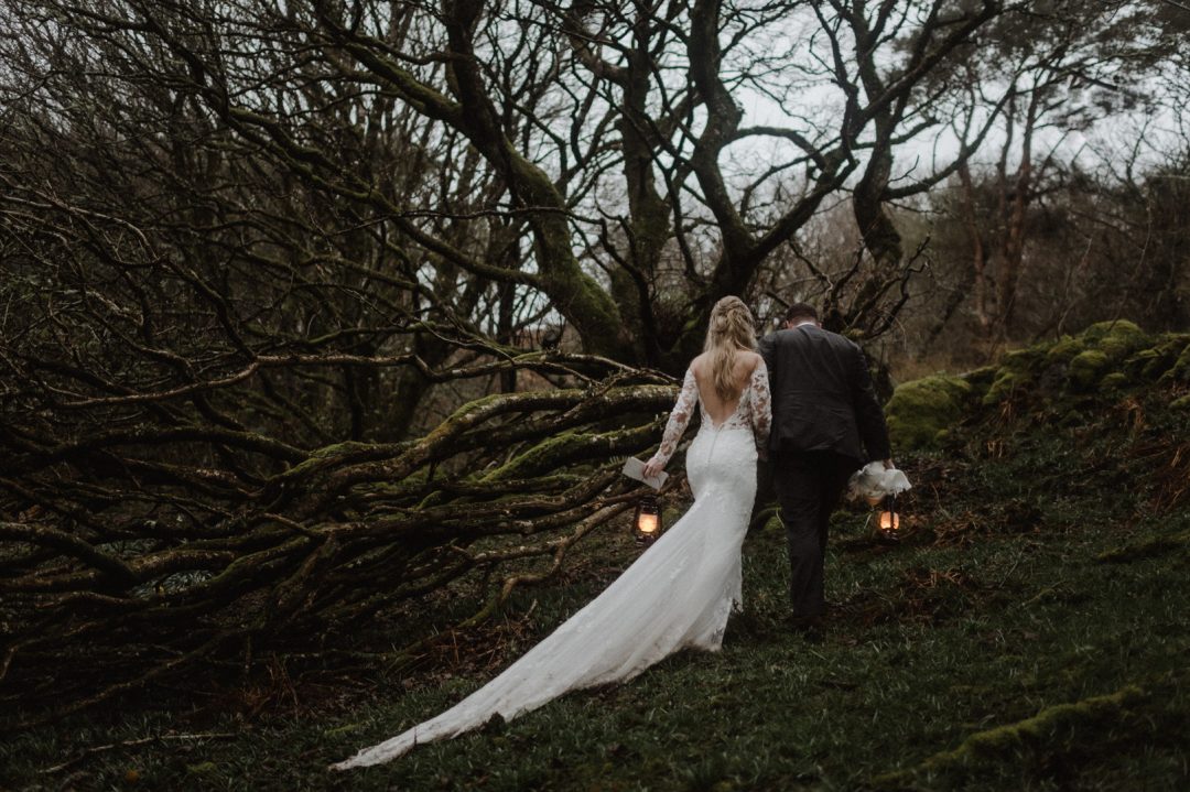 Bride and groom walking up to a magical twisty tree with lanterns and letters at Isle of Skye elopement