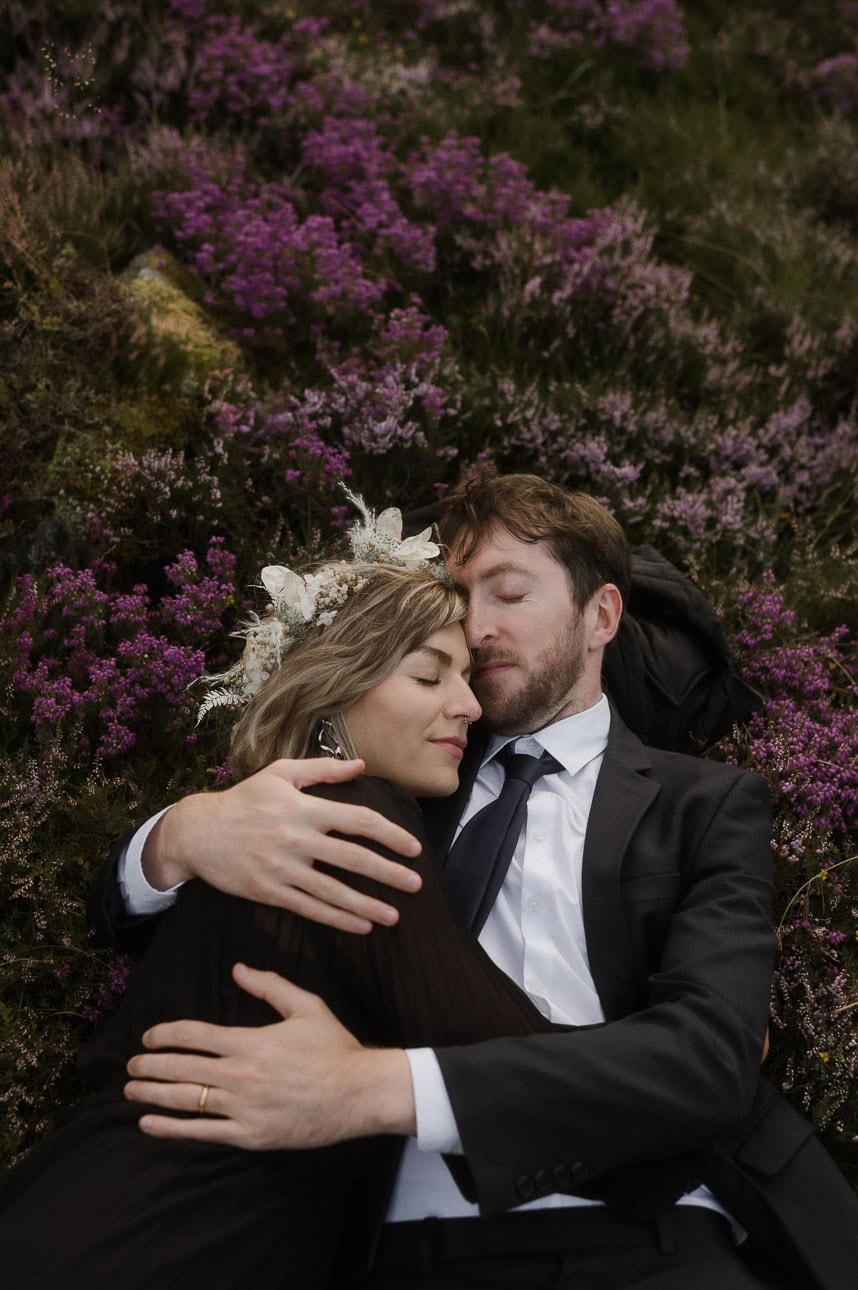 Couple cuddling with the heather bloom during Cairngorms mountain elopement